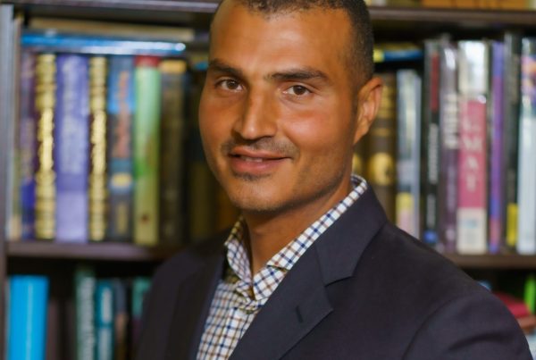 Loay Elbasyouni in front of bookshelves.
